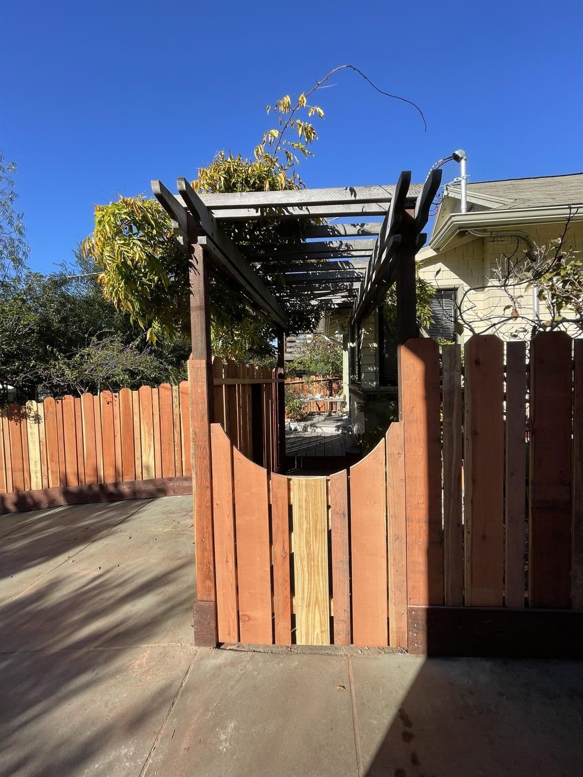 Custom redwood gate with pergola-style arbor built by Romero Máster Fence